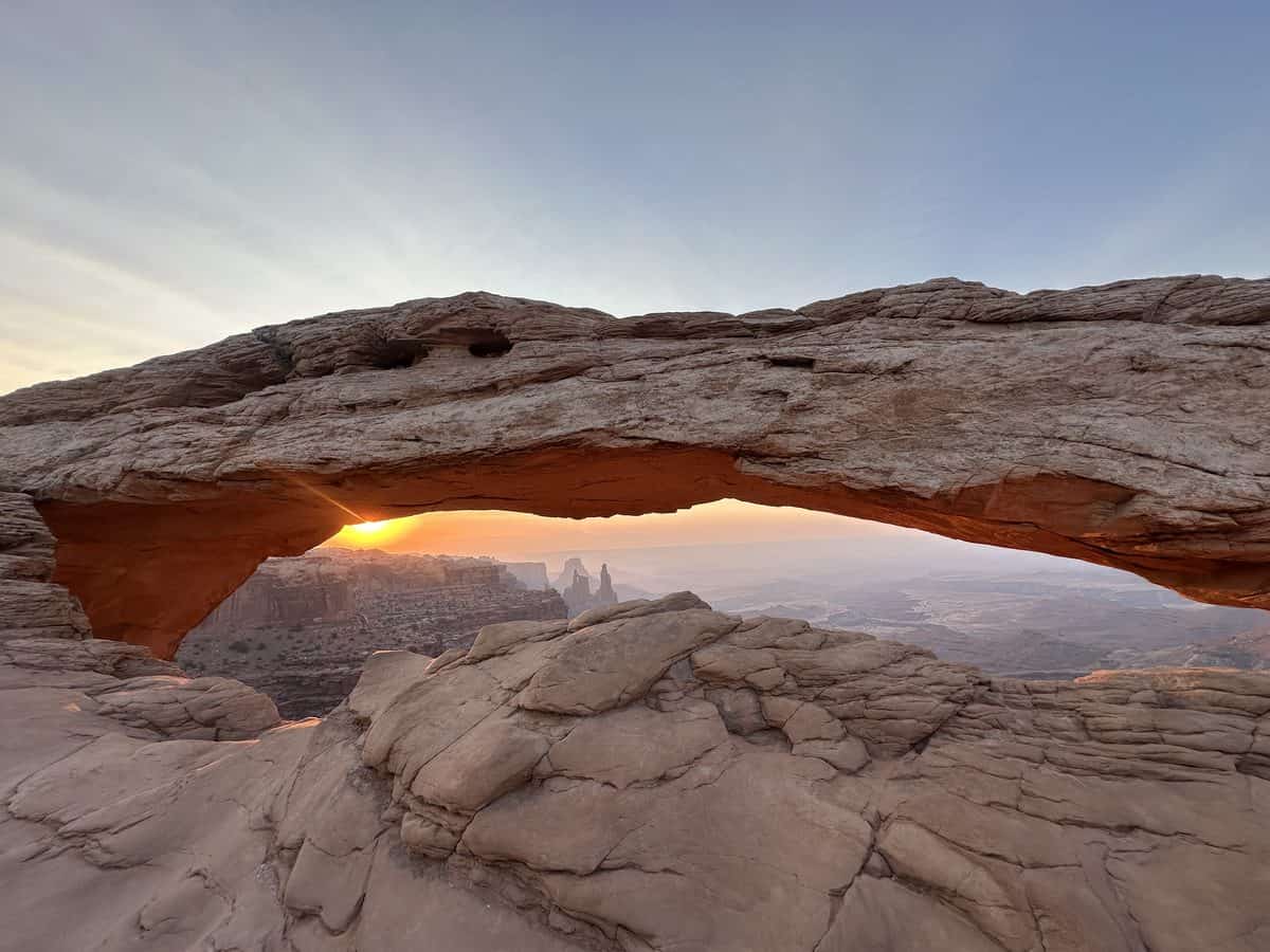 Mesa Arch glowing orange at sunrise in Canyonlands