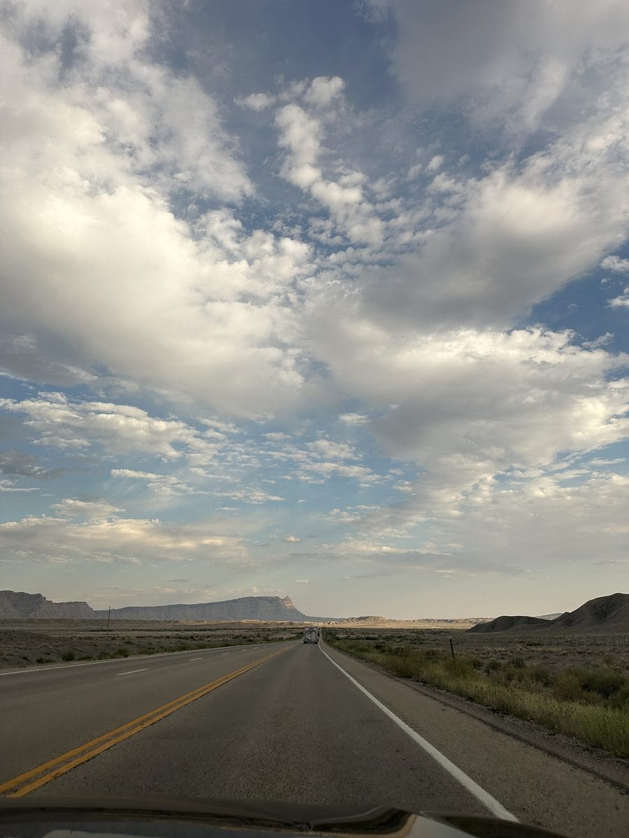 Highway driving into Moab with red rock mesas under a dramatic sky