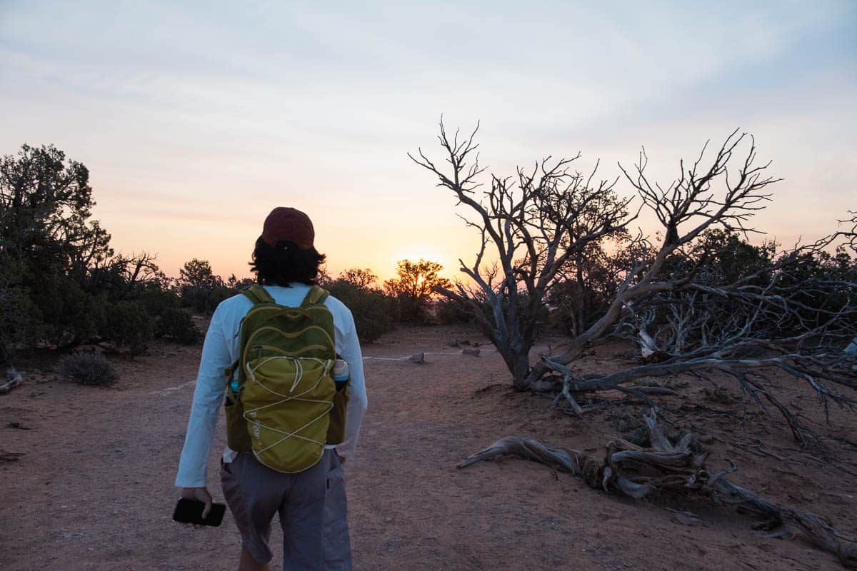 Hiker with a daypack on a sunrise trail near Moab