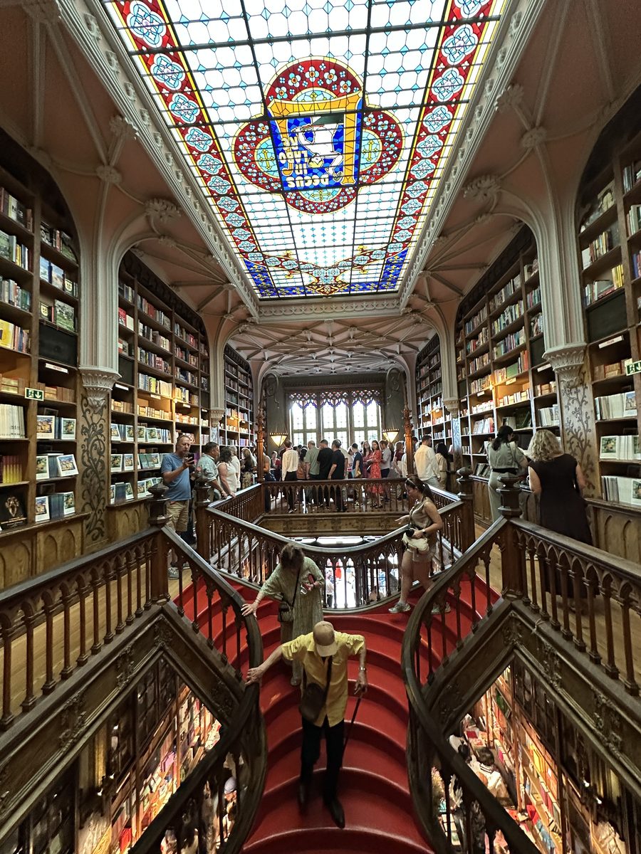 Red staircase and stained glass ceiling inside Livraria Lello bookstore