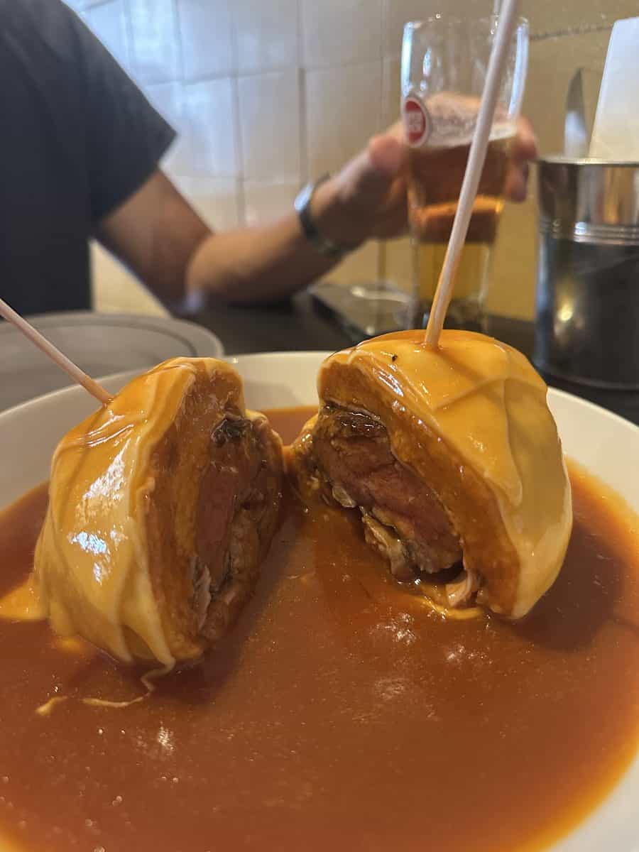 Francesinha sandwich covered in tomato and beer sauce at a Porto restaurant